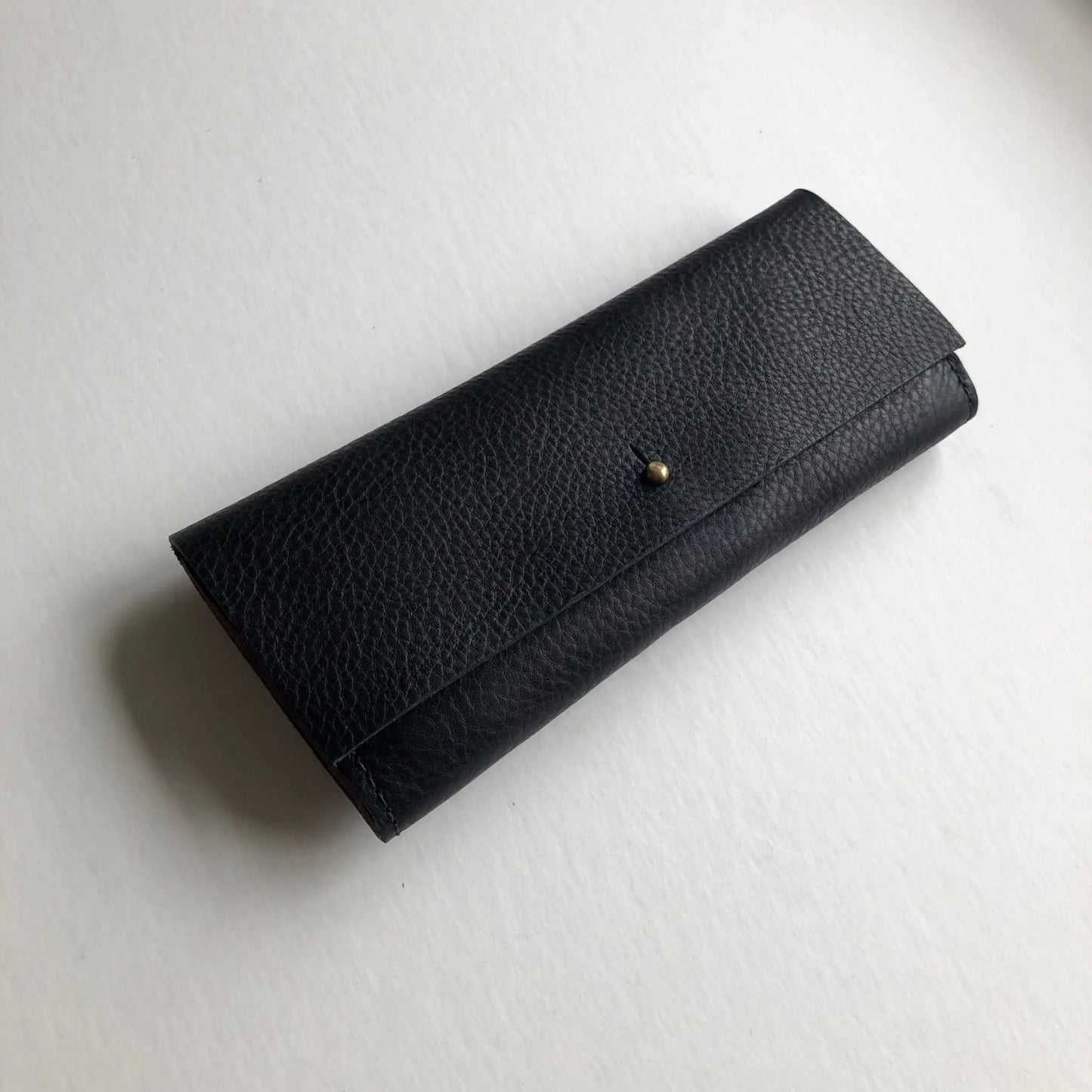 Nomad Midi Leather Purse Wallet in black with smooth brass press-stud closure, handcrafted from sustainable vegetable-tanned leather.