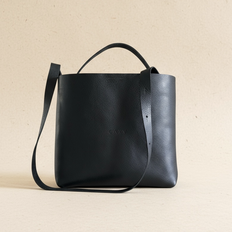 Black leather tote handbag on a beige background