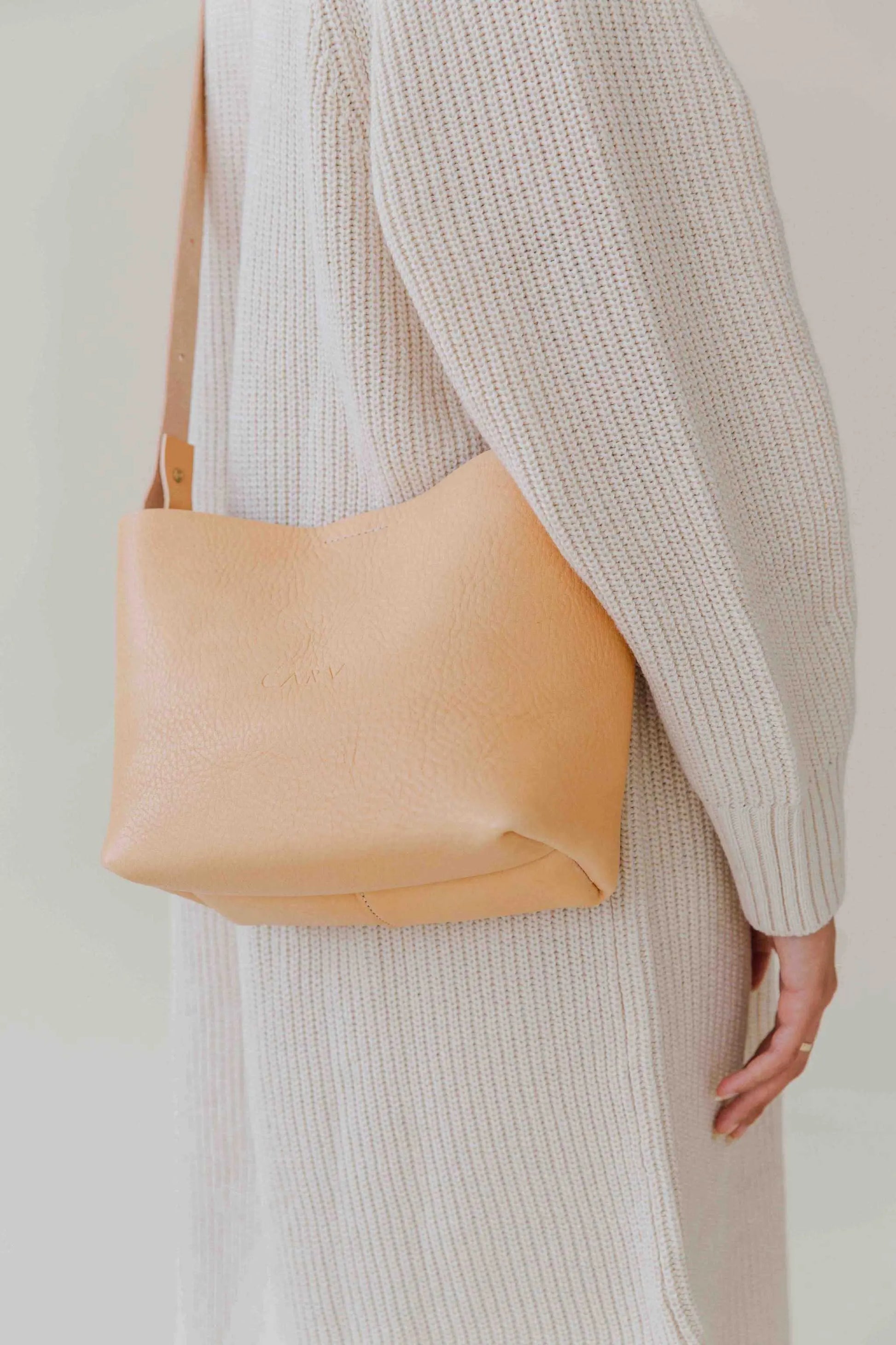 Basket Mini Leather Tote Bag in tan, worn by a person in a cozy sweater.