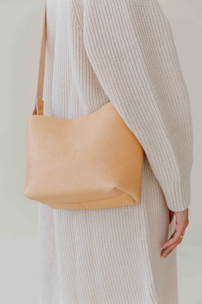Basket Mini Leather Tote Bag in tan, worn by a person in a cozy sweater.