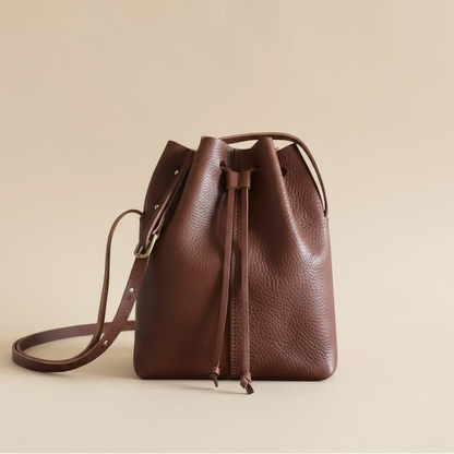 Brown leather drawstring bag on a beige background
