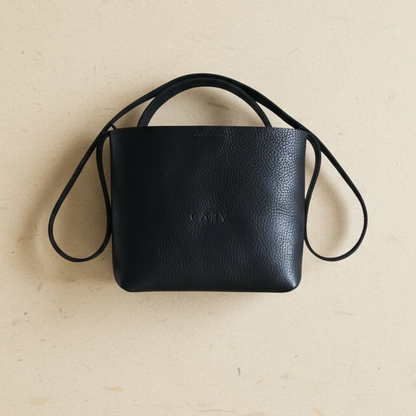 Black leather handbag with a strap on a beige background