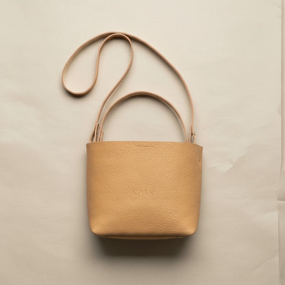 Beige leather tote handbag with a strap on a beige background